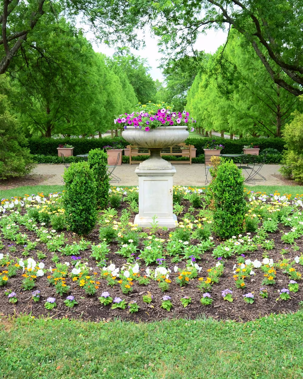 Circular parterre flower bed with a stone urn centerpiece