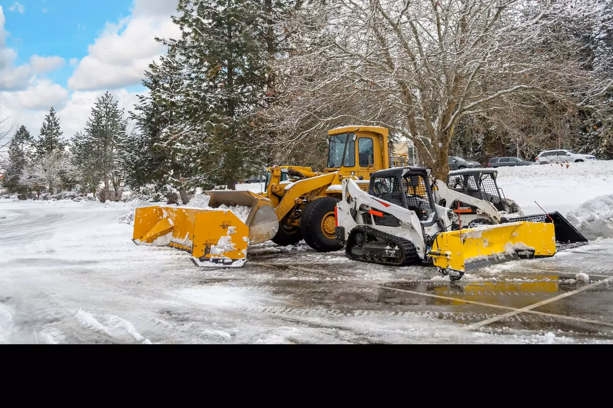 Snow removal fleet with plows clearing a commercial lot