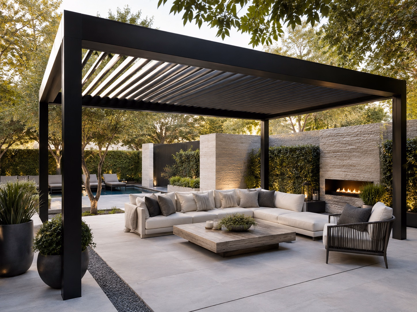 Modern black steel louvered pergola over an outdoor lounge with a stone fireplace on large-format pavers