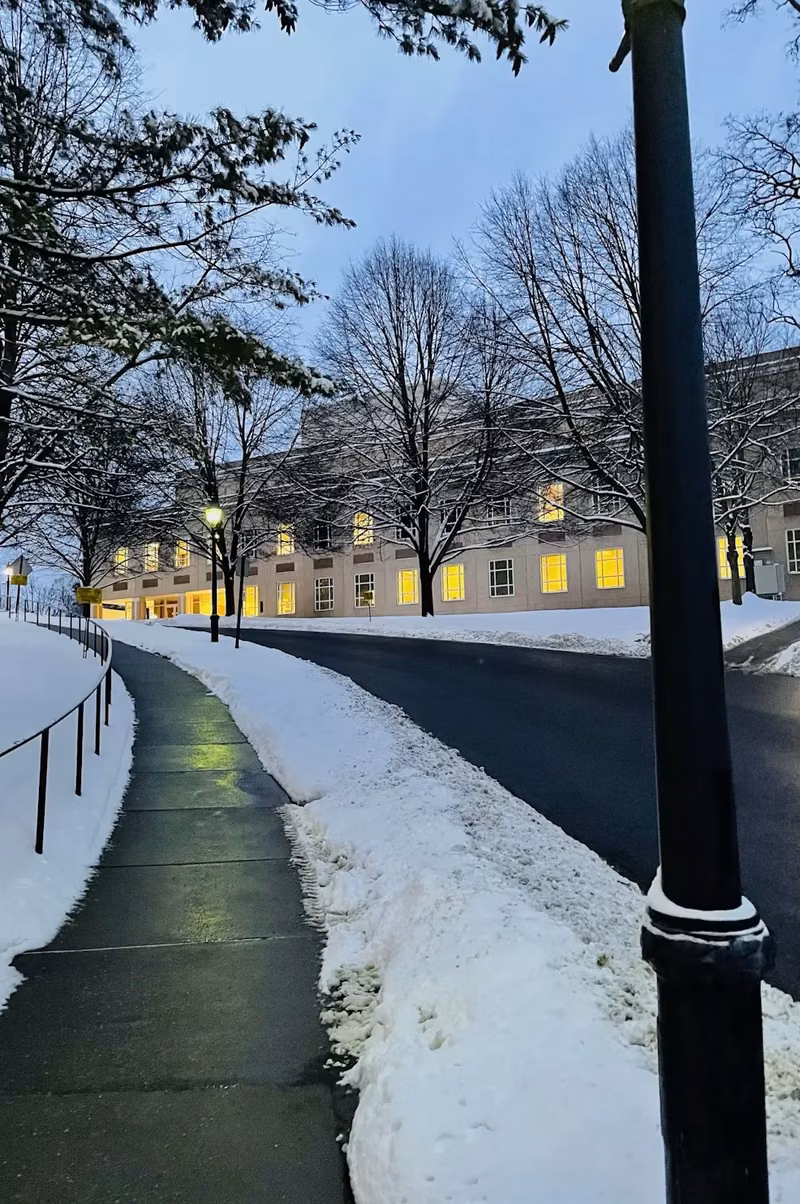 A cleared, treated walkway alongside a commercial building at dusk after snowfall